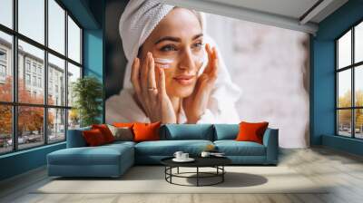 Woman applying moisturizing face cream Wall mural