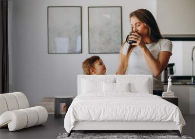 Young mother with little son drinking water at home Wall mural