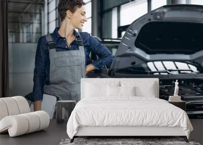 Young woman car mechanic checking car at car service Wall mural