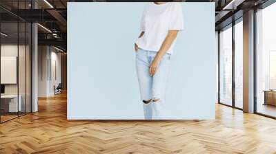 Young woman standing in white shirt isolated on blue background Wall mural