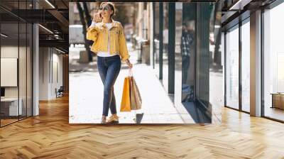 Young woman with shopping bags in the city Wall mural