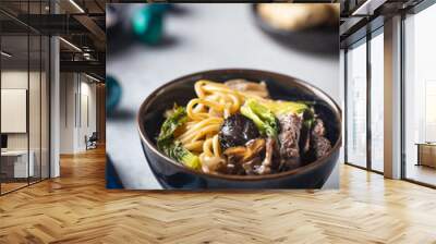 Asian ramen noodles soup with beef, oyster mushrooms and vegetables in bowl on gray background Wall mural