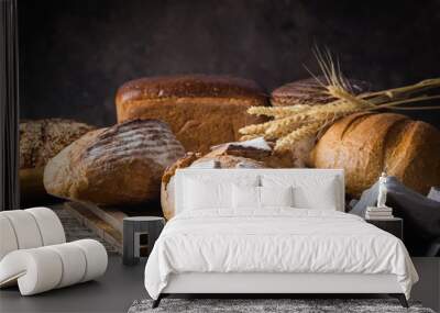 Assortment of fresh baked bread and buns on wooden table background Wall mural