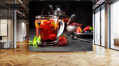 Fruit red tea with berries in glass cup on black background Wall mural