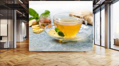 Ginger tea in a glass cup with lemon and mint on light background Wall mural