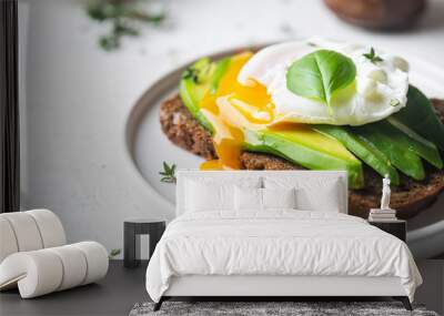 Healthy breakfast whole wheat toasted bread with avocado and poached egg over white background Wall mural