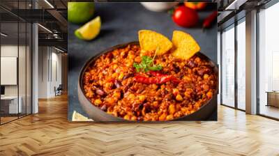 Mexican hot chili con carne in a bowl with tortilla chips on dark background Wall mural