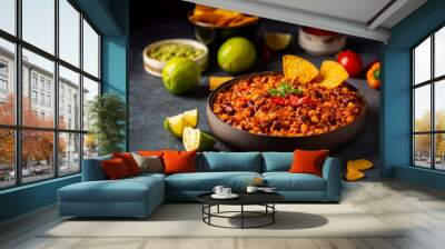 Mexican hot chili con carne in a bowl with tortilla chips on dark background Wall mural