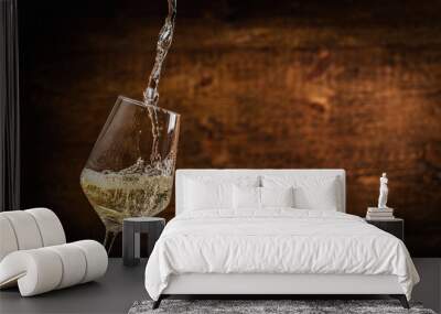 Pouring white wine into the glass on rustic dark background. Pour alcohol, winery concept. Wall mural