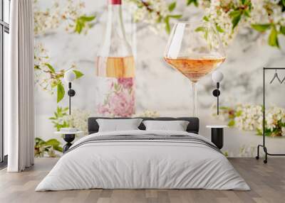 Rose wine glass against white wall with spring cherry flowers. Refreshing alcoholic summer drink or nature concept. Wall mural