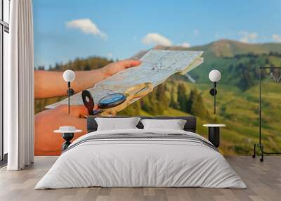 Tourist's hand with a map and compass in the mountains Wall mural