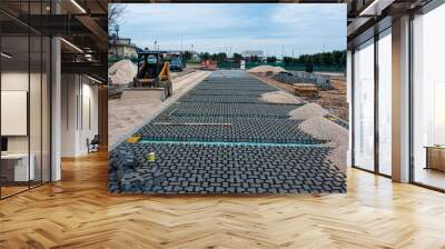 Paving stone worker is putting down pavers during a construction of a city street. Wall mural