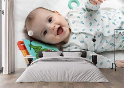 Cute smiling infant lying in his bed with different toys Wall mural