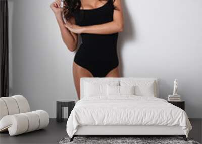 Brunette in a black bodysuit and black socks on a white background.Sexy Brunette. Wall mural