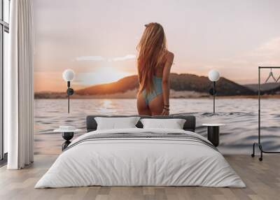 Girl with a gorgeous figure on the sea during sunset.Sexy girl on a wild beach.The girl in the water Wall mural