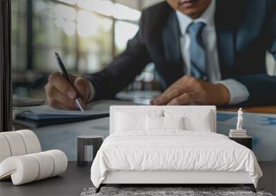 A businessman writing on paper is sitting on the desk. Wall mural