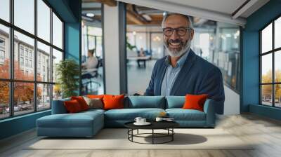 Happy businessman smiling with tablet, phone, and laptop inside the modern office. Wall mural