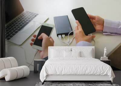 Two office staff hands hold of the phone and charger. Powerbank and smartphone in staff hands. Energy charger power bank smart phone. Still life modern digital concept. Wall mural