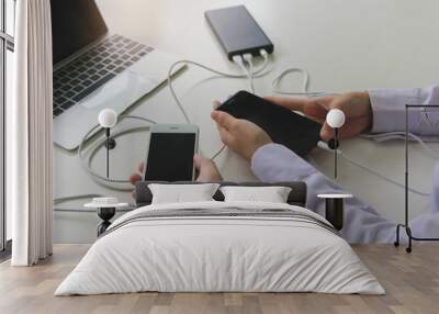 Two people using two mobile phone sharing USB Power Bank on a table to charge the mobile devices.Technology device charge sharing concept. Wall mural