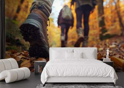 A close-up shot of hiking boots walking on a trail covered in fallen autumn leaves Wall mural