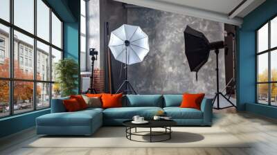 A professional photo studio setup featuring two umbrellas and a camera, ready for a photography session. The studio is equipped with various illumination tools for capturing high-quality images. Wall mural