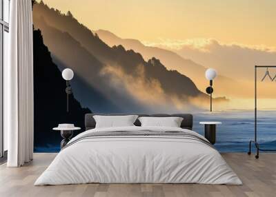 Morning light casts a warm glow over rugged cliffs and gentle waves, creating a tranquil coastal landscape Wall mural