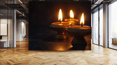 A traditional brass Diya holder with lit oil lamps, glowing brightly against a dark background for Diwali. Wall mural