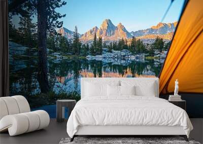 Close-up of a camping tent in focus, with a scenic view of a pristine lake and rugged mountain peaks reflecting under the evening light. Wall mural