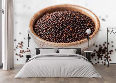 Close-up of mustard seeds piled in a small ceramic dish, with a few scattered around on a white background, no people. Wall mural