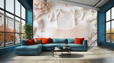 Top view of a collection of baby girl clothes, focusing on a tutu, with a headband, socks, and a floral top on a light surface. Wall mural