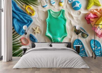 Top view of a collection of kids' swimwear, with the focal point on a bright green swimsuit, surrounded by a towel, goggles, and flip-flops on a sandy background. Wall mural