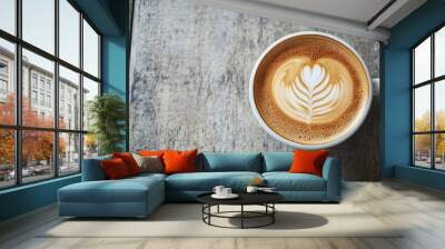 Top view of a cup of coffee with delicate latte art, placed on a rustic wooden table with a textured grain. No logo, no people. Wall mural