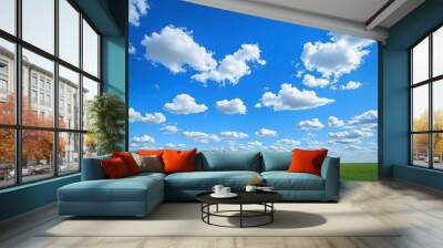 A bright, blue sky with small cotton-like clouds scattered across it, viewed from a wide-open field. Wall mural