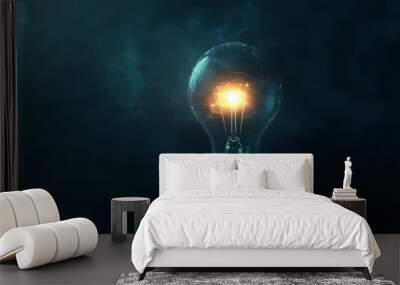 A glowing light bulb surrounded by darkness, symbolizing innovation and bright ideas shining through. Wall mural