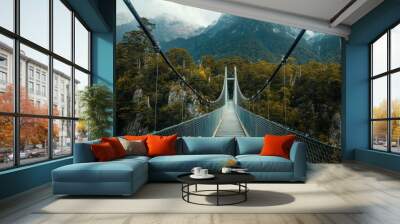 A suspension bridge swaying slightly in the wind, with mountains towering in the background. Wall mural