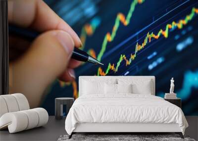 Close-up of hands writing on a financial growth chart beside stock market analysis reports. Wall mural