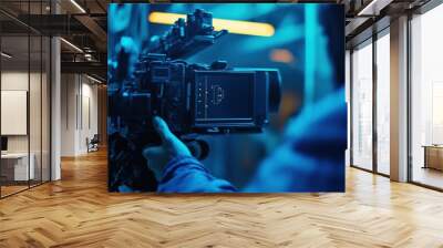 Camera operator in a lit dark blue room with film equipment Wall mural