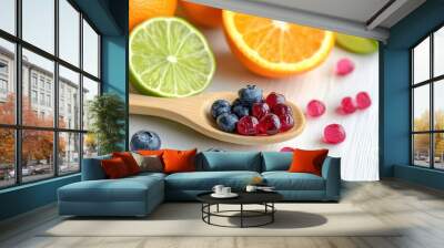 Wooden spoon with multivitamins and healthy fruits blueberry lime orange pomegranate on a white background Wall mural