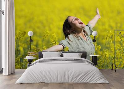 Excited woman celebrating spreading and screaming in a field Wall mural