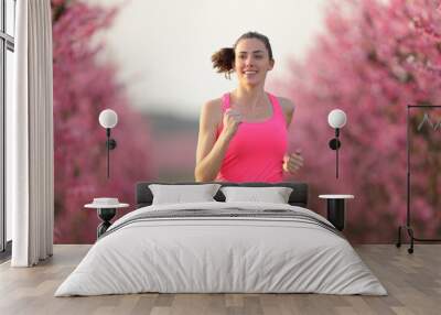 Front view of happy runner running in a pink field Wall mural