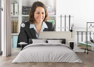 Happy executive lady working on laptop at office Wall mural