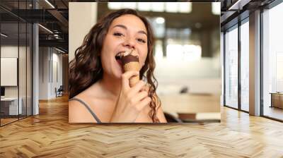 Happy woman eating ice cream looking at you in a bar Wall mural