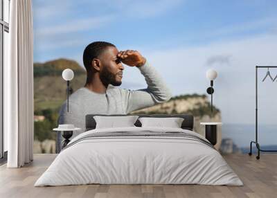 Man with black skin contemplating with hand on forehead Wall mural