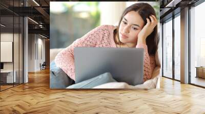 Serious woman using laptop sitting at home Wall mural