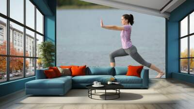 Side view of a woman doing tai chi exercise in a lake Wall mural