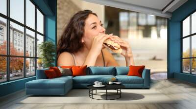 Woman eating sandwich in a coffee shop Wall mural