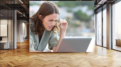 Woman forcing sight wearing eyeglasees reading laptop Wall mural