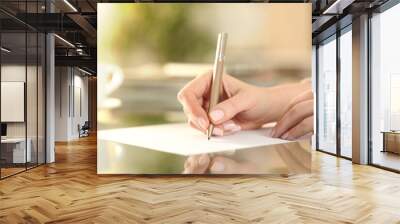 Woman hand writing on a paper on a desk at home Wall mural