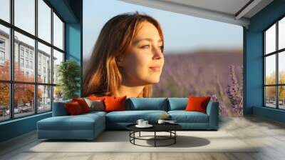 Woman relaxing contemplating sunset from lavender field Wall mural