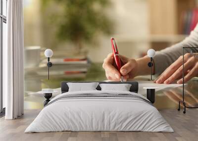 Woman signing document with pen on a desk at home Wall mural